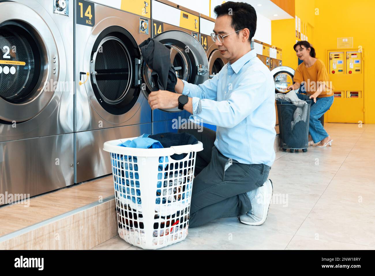 Asian people using qualified coin operated laundry machine in the public room to wash their cloths. Concept of a self service commercial laundry and Stock Photo