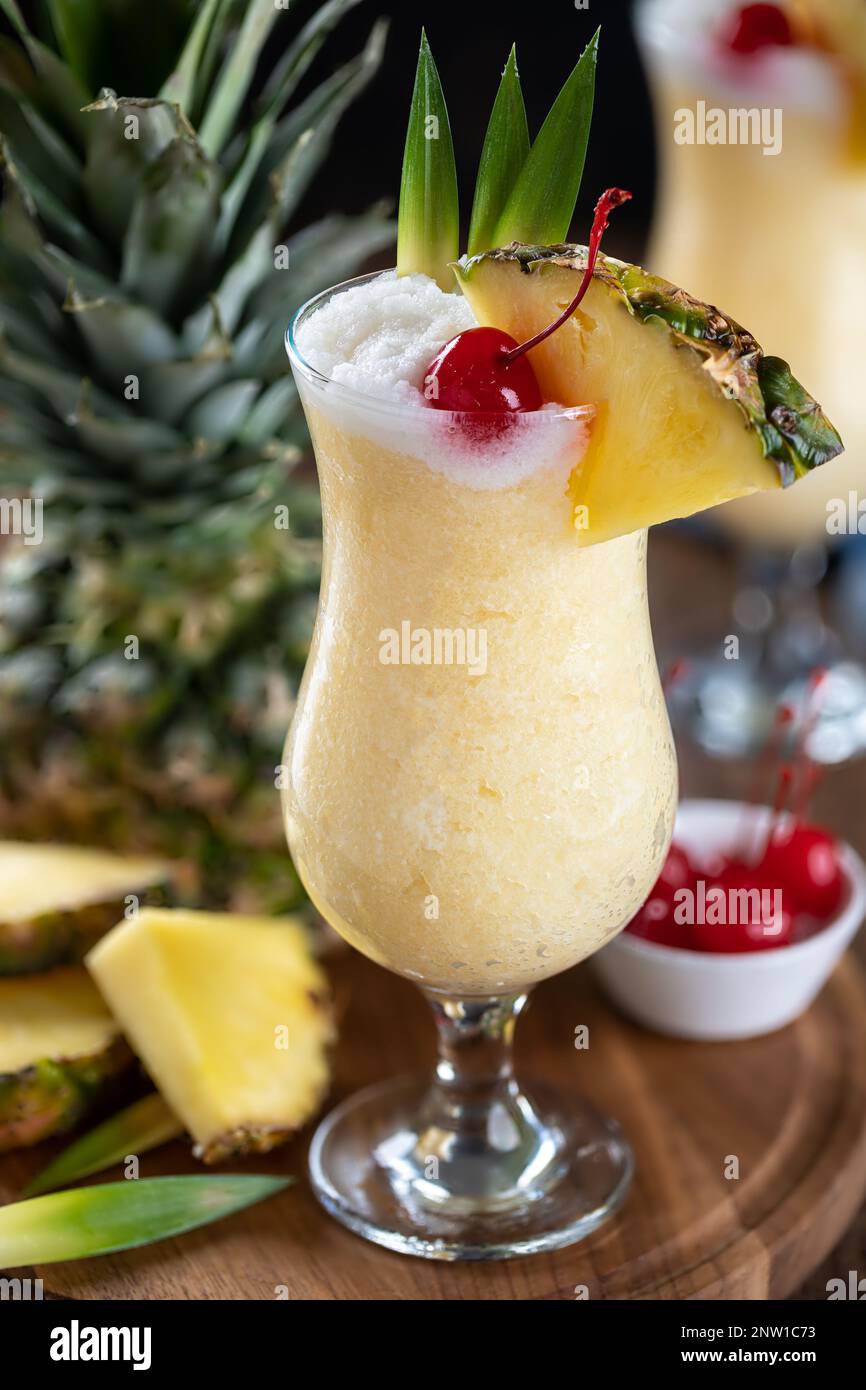 https://c8.alamy.com/comp/2NW1C73/pina-colada-cocktail-garnished-with-cherry-pineapple-slice-and-leaves-on-a-wooden-platter-2NW1C73.jpg