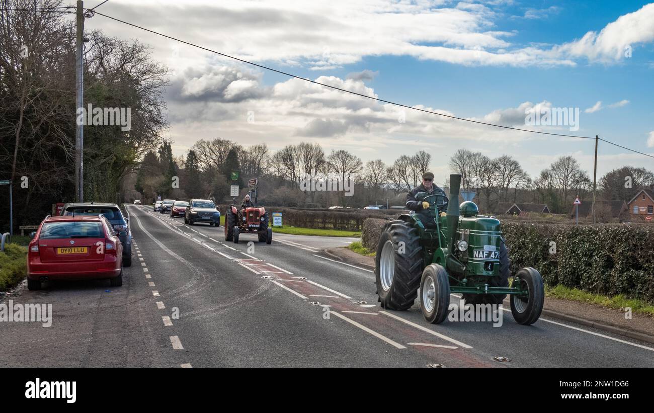 An enthusiast drives his vintage Field Marshall tractor and is follwed by another vintage tractor and a line of cars in Wisborough Green, UK. Stock Photo