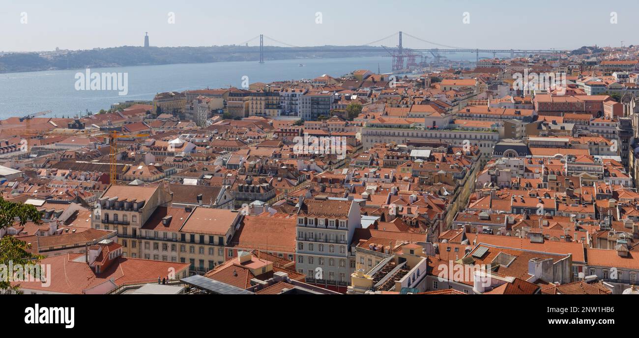 Lisbon, Portugal: A panoramic view of the cityscape from the walls of São Jorge Castle, showing terracotta rooftops, the Tagus River, and the 25 de April Bridge in the distance.