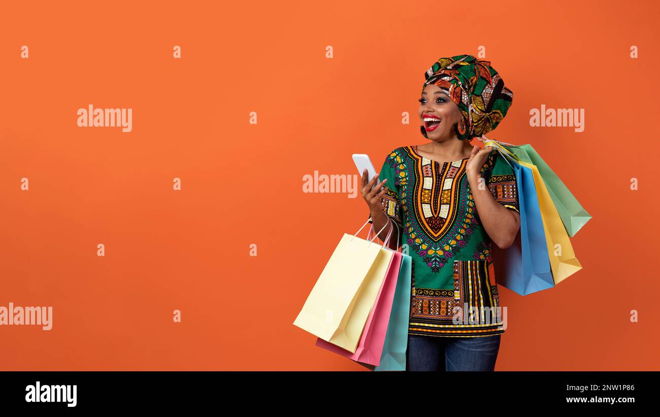 Emotional black woman in african costume shopping online copy space