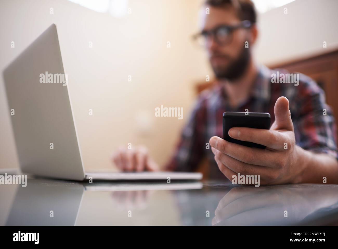 Using all the latest tech. Shot of a handsome young hipster working on a laptop. Stock Photo