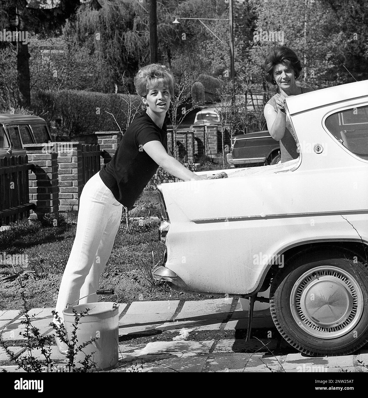 In the 1960s. Actress singer Lill-Babs washing her car, a Ford Anglia. her mother to the right. Sweden 1964 Stock Photo