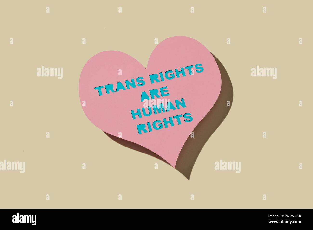a pink heart-shaped cardboard sign with the text transgender rights are human rights, on a pale yellow background Stock Photo