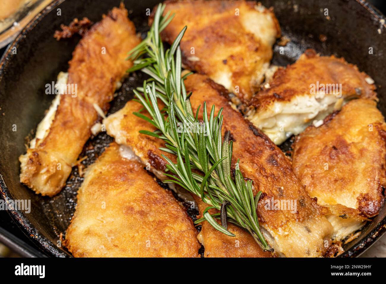 pieces of fried flounder in a frying pan seasoned with rosemary Stock