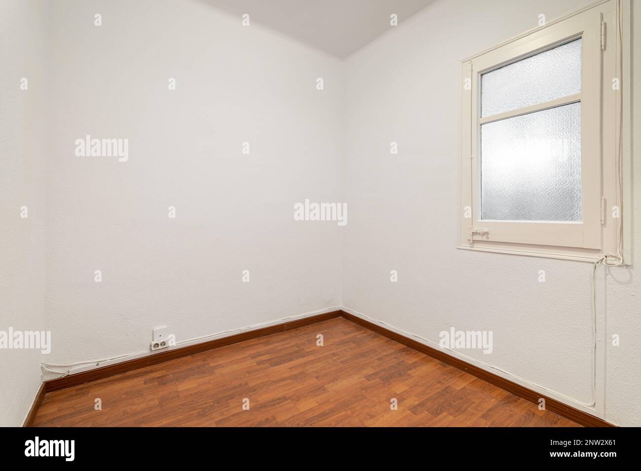 Empty room with laminate flooring, newly painted white walls and bright