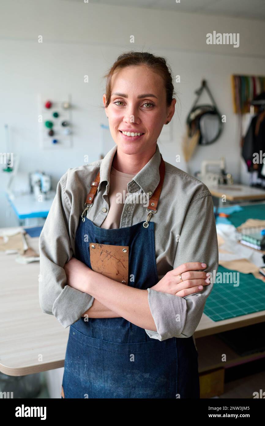 Young successful female leather worker and owner of atelier in apron ...