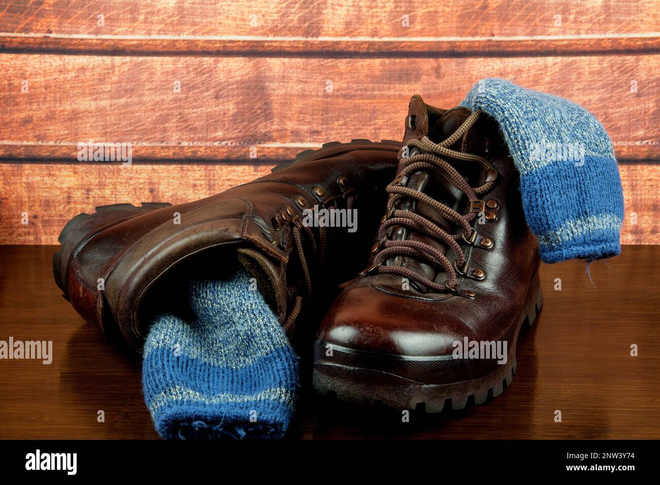 Old hiking boots with socks on a polished wooden surface Stock Photo