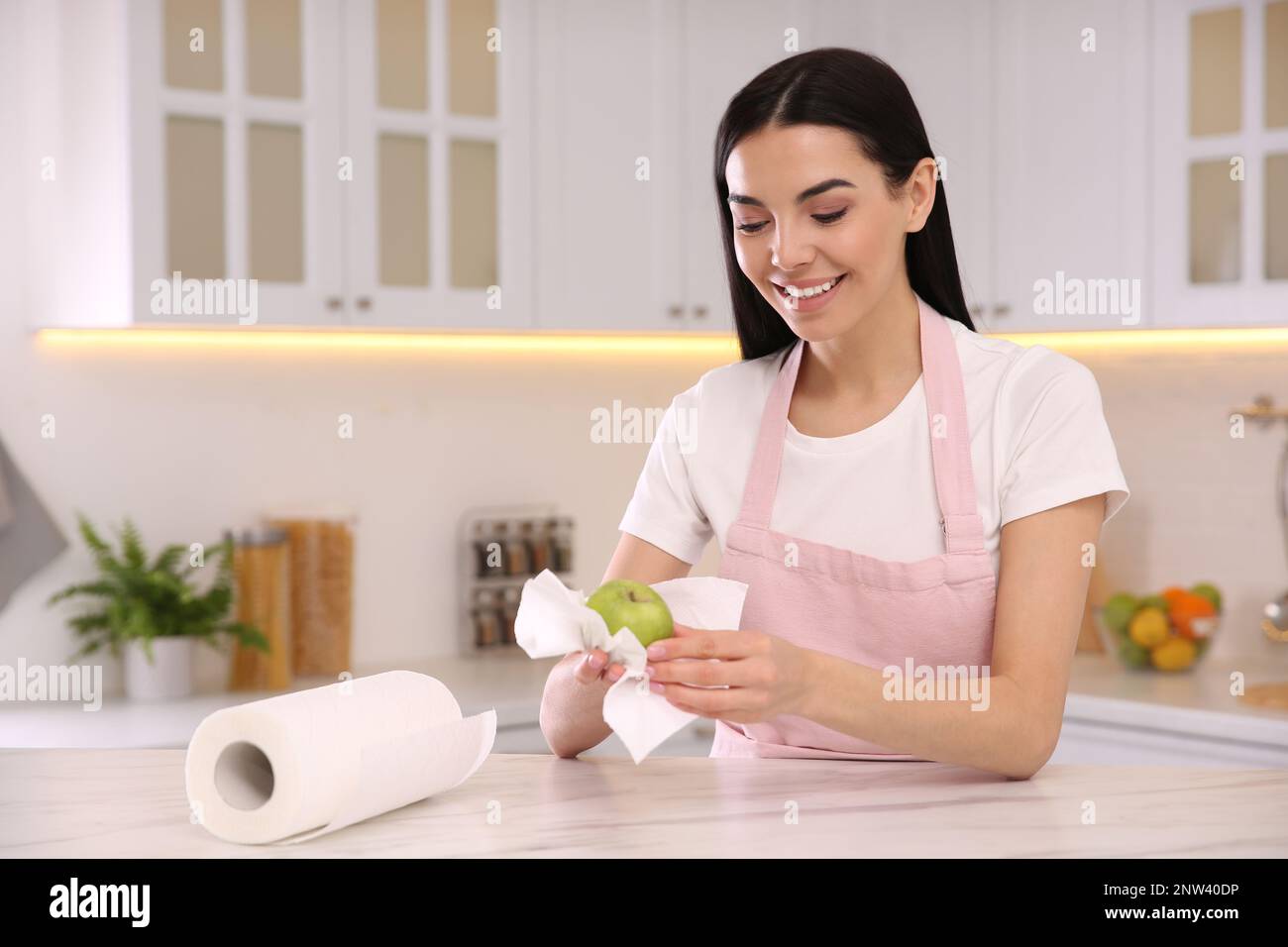 Woman wiping green apple with paper towel in kitchen Stock Photo Alamy