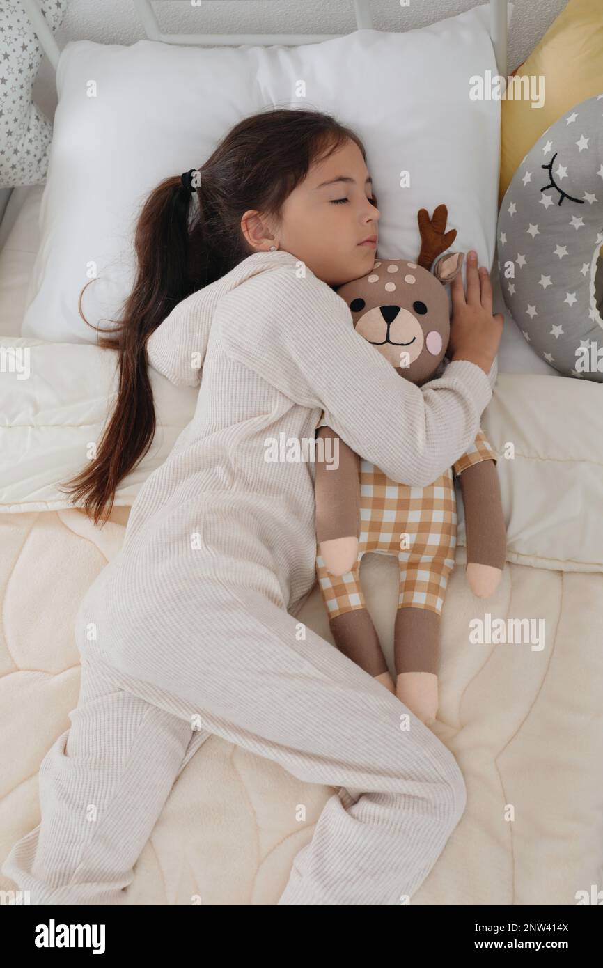 Cute girl in pajamas sleeping with toy deer at home Stock Photo - Alamy