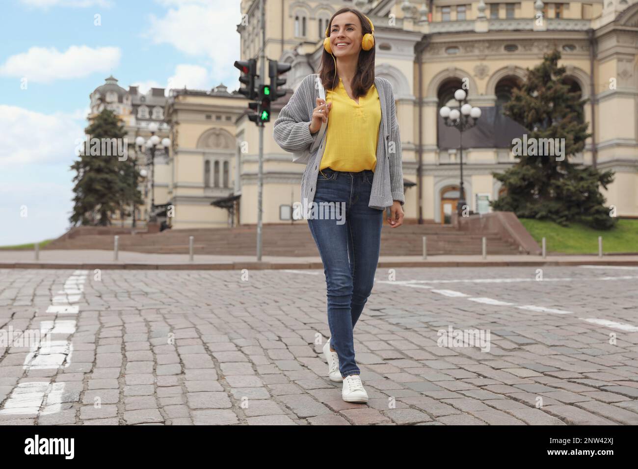 Young woman with headphones crossing street. Traffic rules and