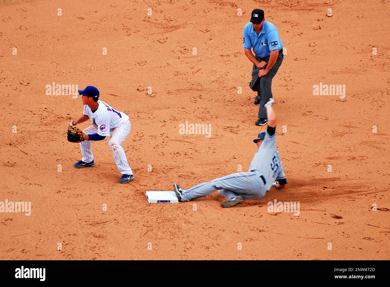 A San Diego Padre slides into second base at a game in Chicago Wrigley Field, Chicago against the Cubs while an umpire prepares to male a call Stock Photo