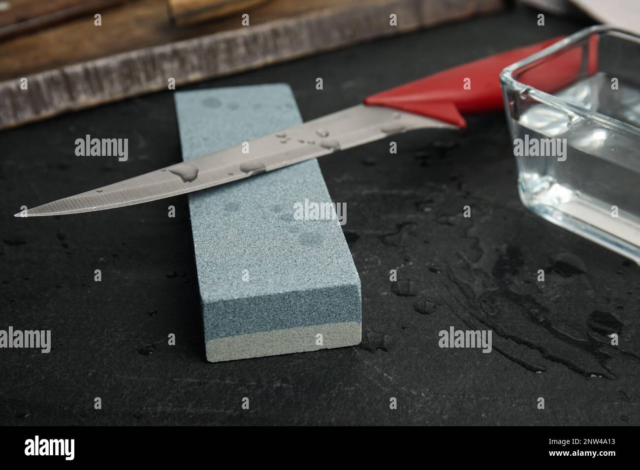 https://c8.alamy.com/comp/2NW4A13/sharpening-stone-knife-and-water-on-black-table-closeup-2NW4A13.jpg