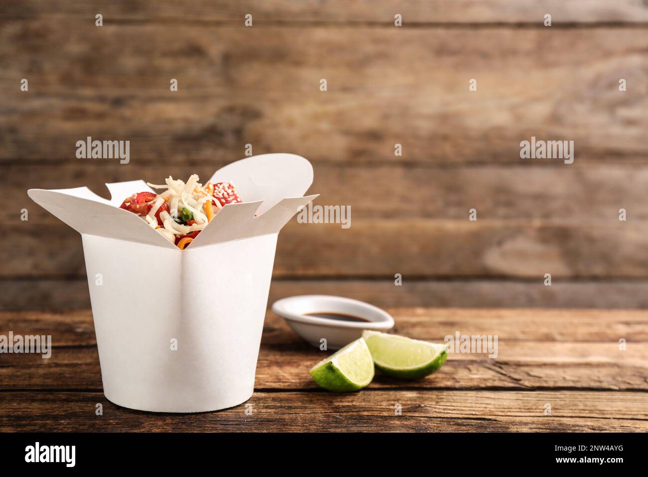 Box of vegetarian wok noodles with lime and soy sauce on wooden table.  Space for text Stock Photo - Alamy