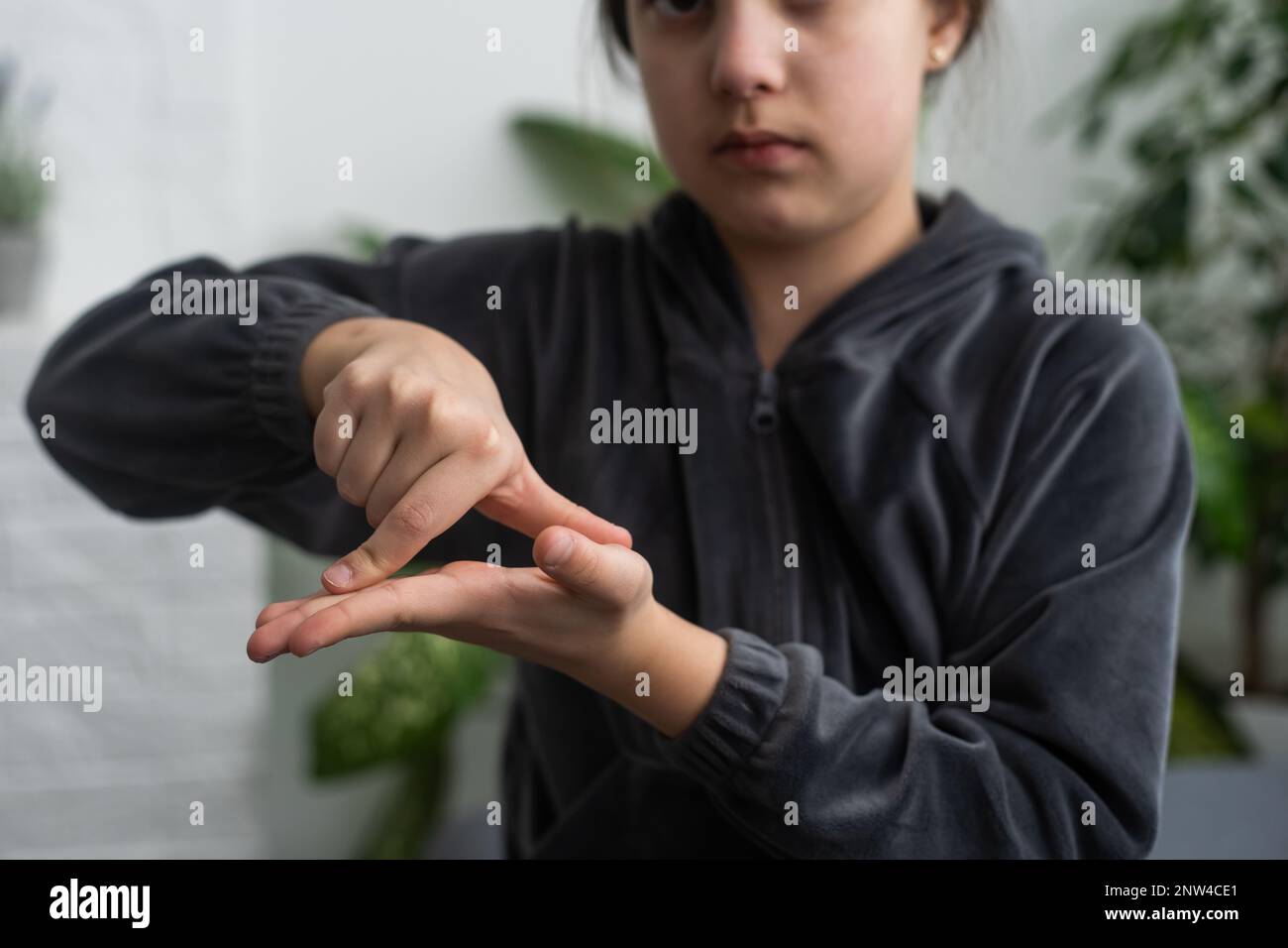 Cute deaf mute girl using sign language on light background Stock Photo