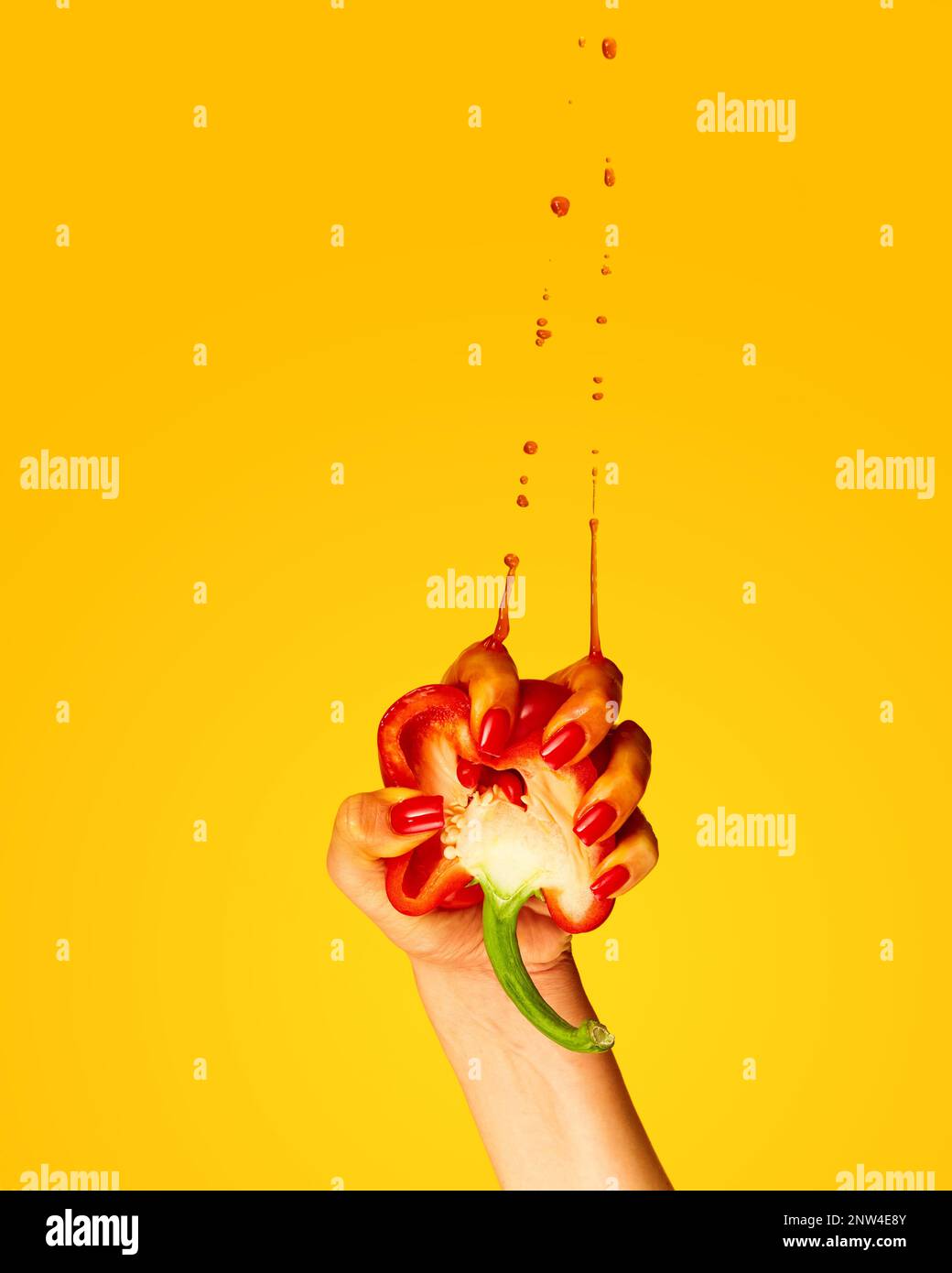 Red pepper juice. Female hand squeeze pepper and drops flying up over