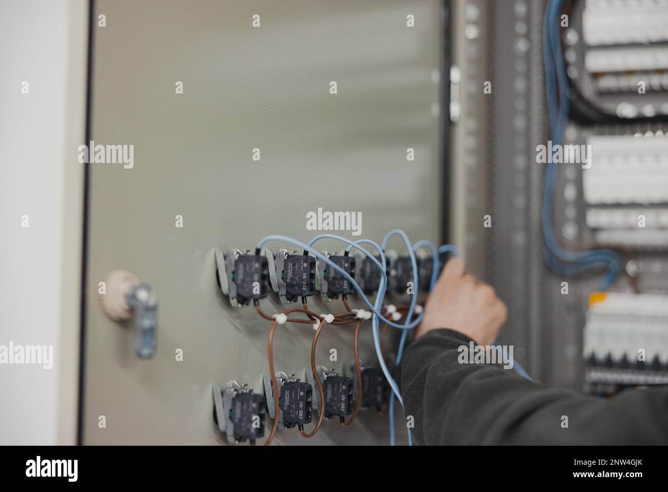 electrician working on electric panel, closeup of hands with wires Stock Photo