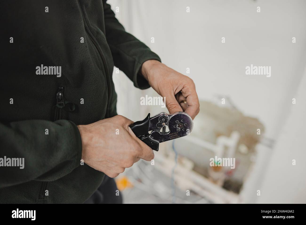 The electrician crimps the cables with pins using special pliers Stock Photo