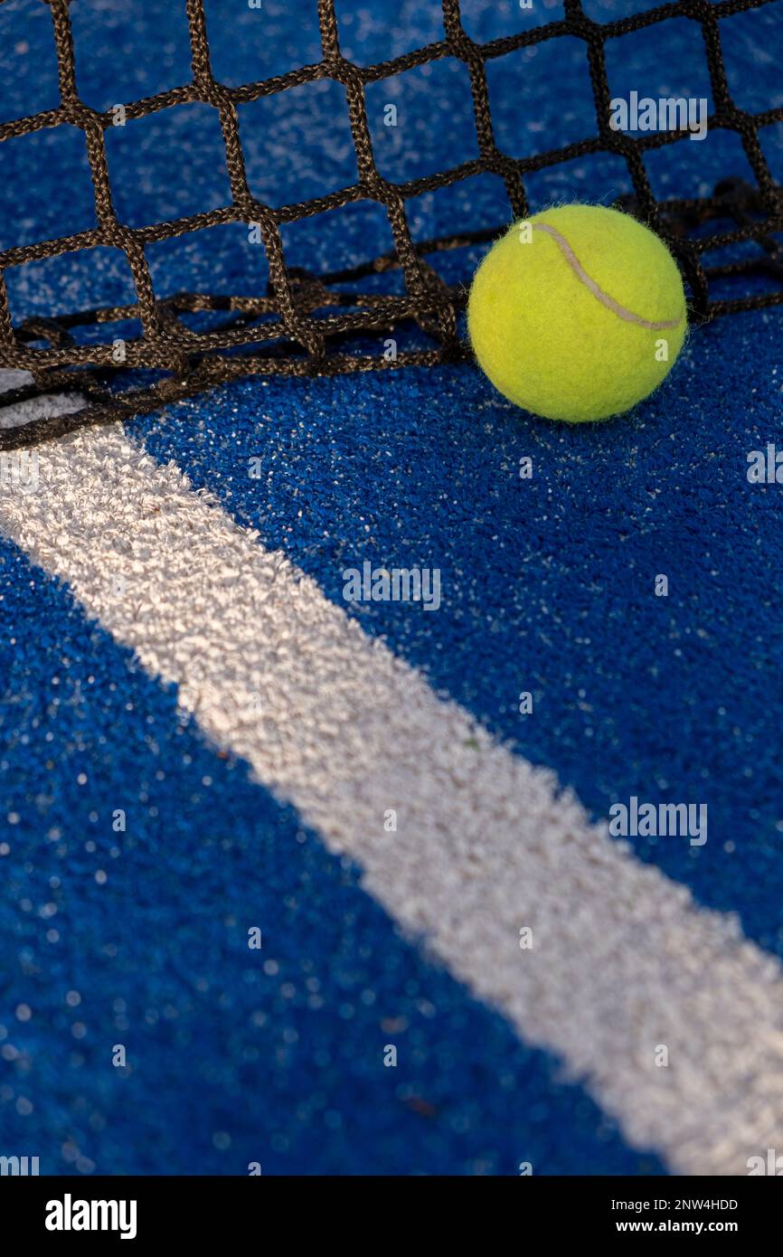 paddle tennis ball in the net of a blue paddle tennis court. Racket
