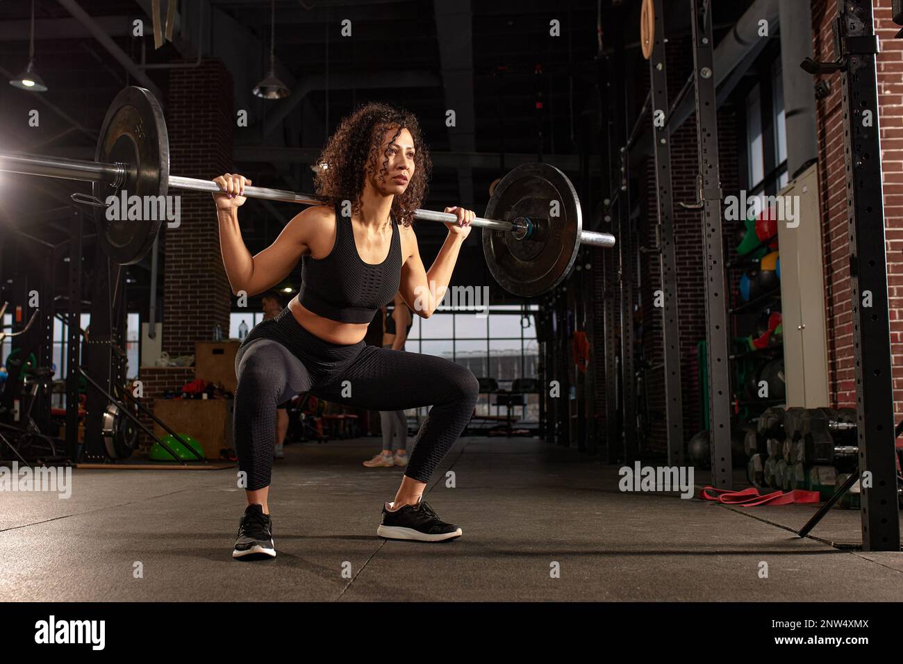 Young pretty african american sports woman in fitness gym lifting up