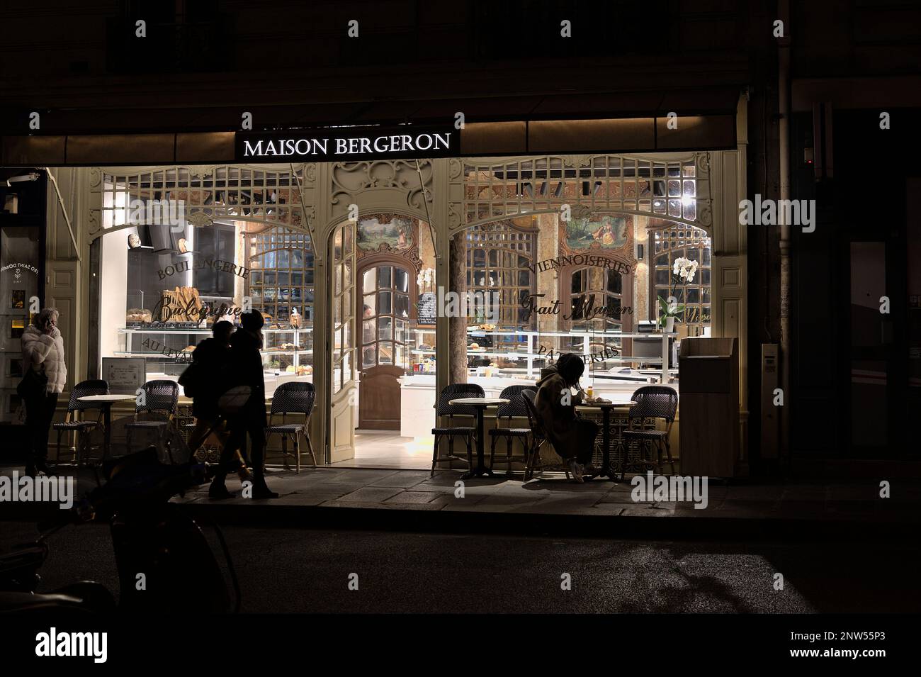 Shadows of people in front of a bakery at night in Paris Stock Photo