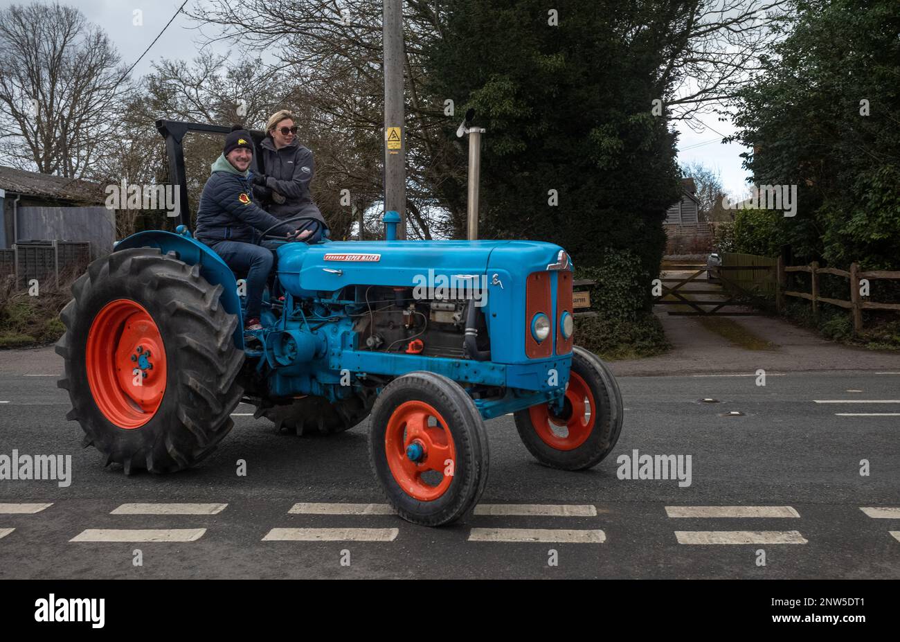 A couple drive along in a vintage Fordson Super Major tractor in Wisborough Green, West Sussex, UK. Stock Photo