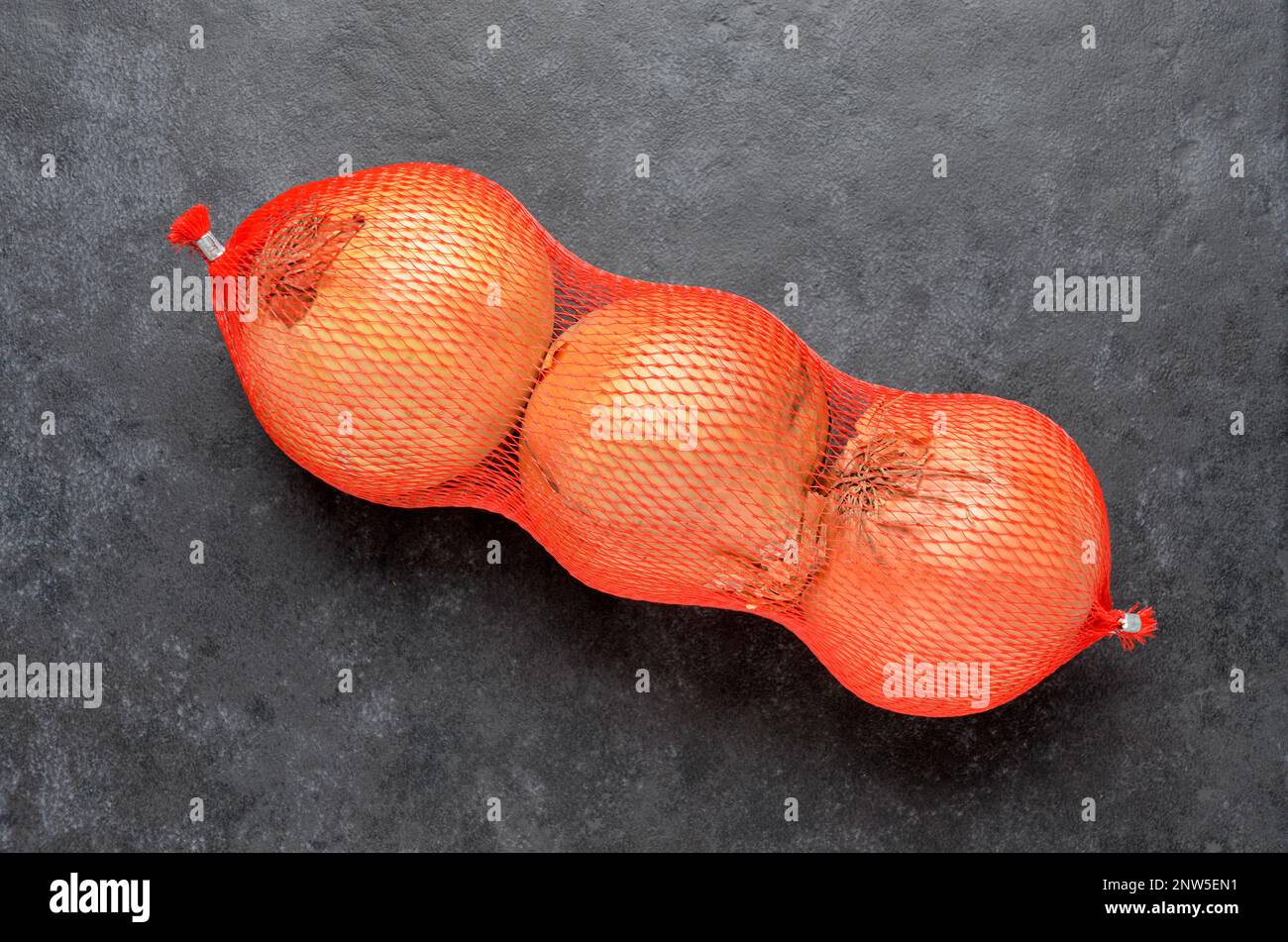 5 kg farm onions in a red pp mesh bag. Polypropylene net sack with 11 lb of  organic onions on a brown floor indoors. Buying fresh vegetables in bulk  Stock Photo - Alamy