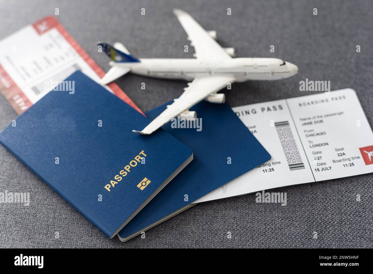 Passports, boarding passes and toy airplane on gray table Stock Photo