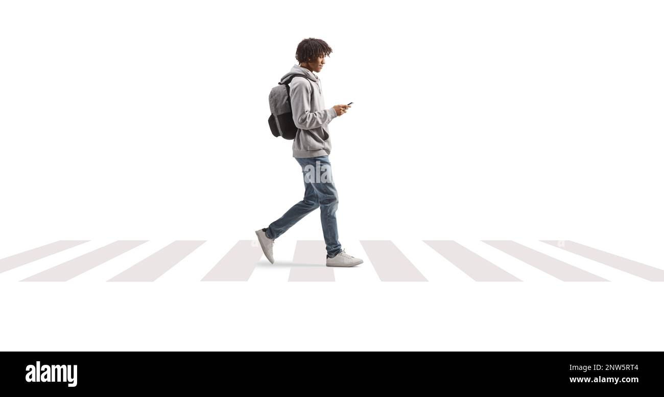 Full length profile shot of a young african american man using a phone and crossing street isolated on white background Stock Photo