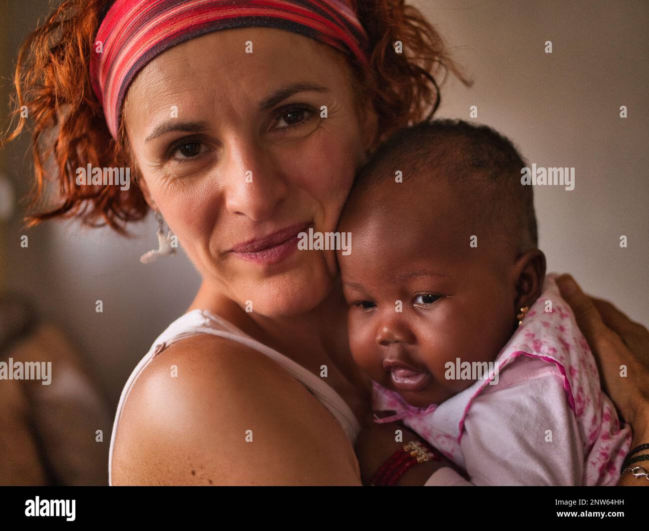 A white woman holds in her arms an african baby Stock Photo
