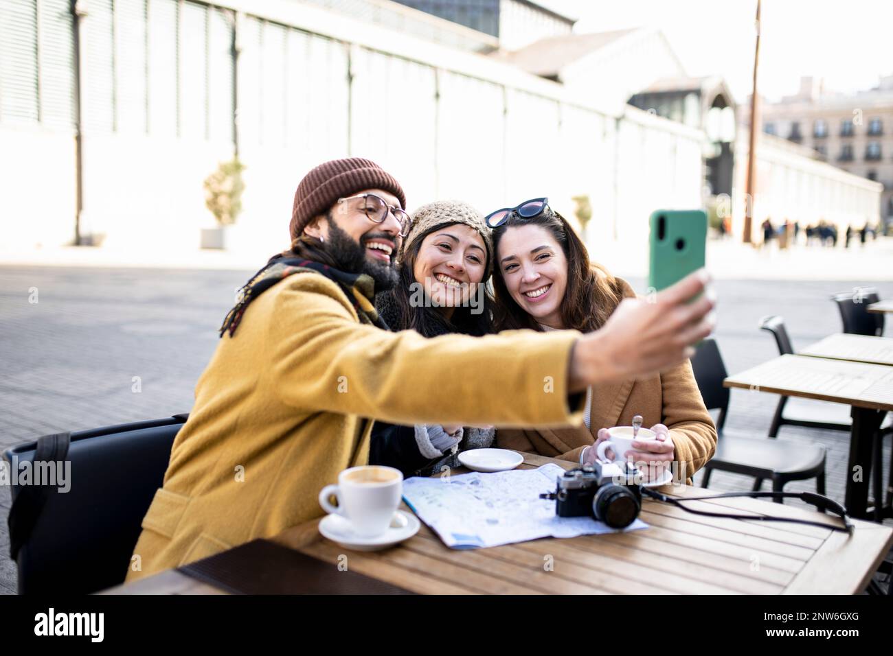 group of three happy friends taking selfie in outdoor cafe on sunny day - cheerful holidays concept Stock Photo