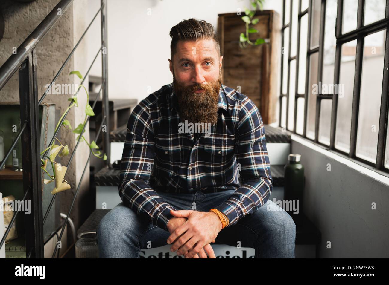 Portrait of hipster man looking at camera.Guy sitting on stairs with confident face. Stock Photo