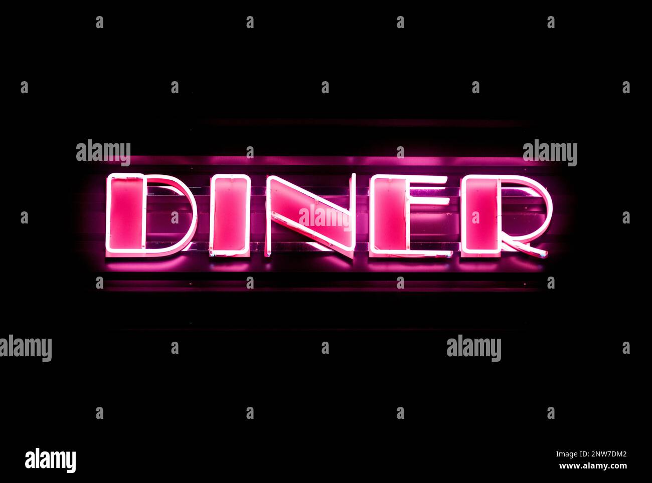 Close-up on a pink neon light shaped into the word 'Diner'. Stock Photo