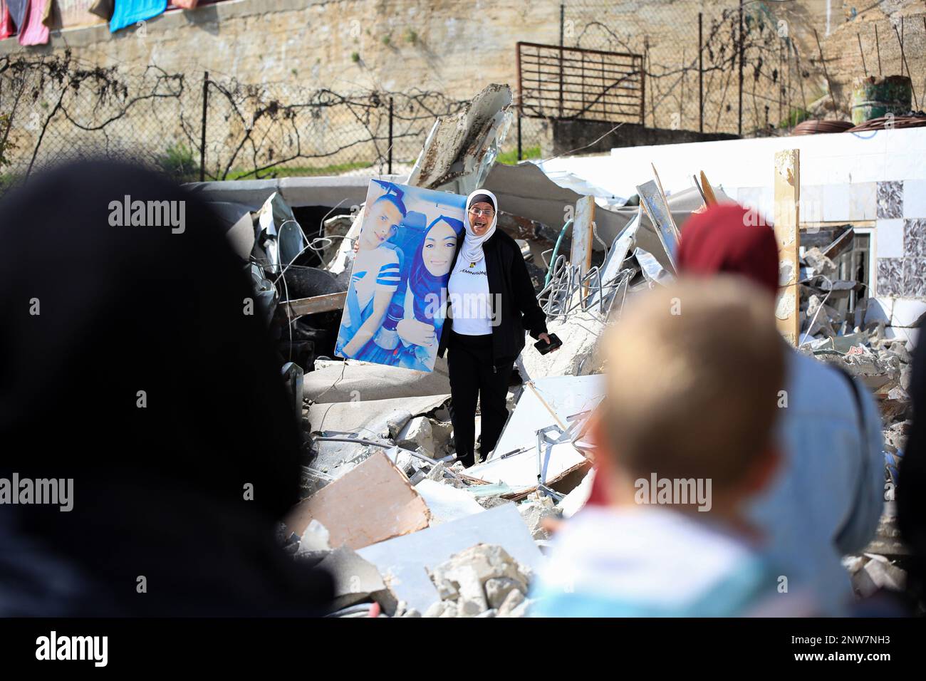 Jerusalem, Israel. 28th Feb, 2023. A woman holds a portrait of relatives after Palestinian Ihab al-Husayni's settlement was demolished by Israel forces for allegedly not having a permit in the Jabal Mukaber neighborhood of East Jerusalem. Credit: SOPA Images Limited/Alamy Live News Stock Photo