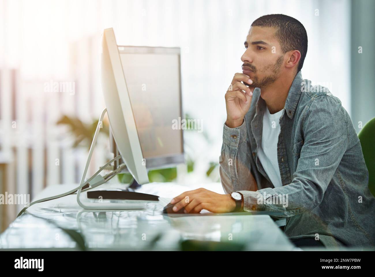 Problem solving is his specialty. Shot of a young designer working at his computer in an office. Stock Photo