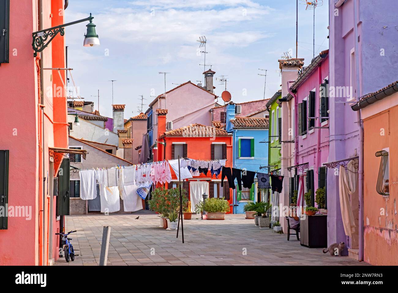 Laundry hanging to dry in alley with brightly coloured houses at Burano, island in the Venetian Lagoon near Venice, Veneto, Northern Italy Stock Photo