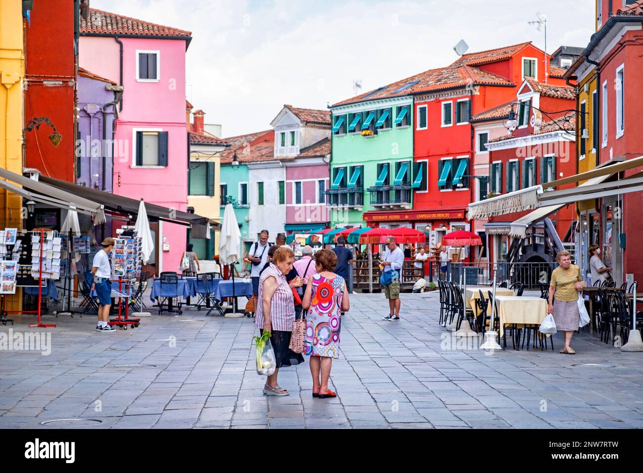 Elderly local women shopping at square with brightly coloured restaurants at Burano, island in the Venetian Lagoon near Venice, Veneto, Northern Italy Stock Photo