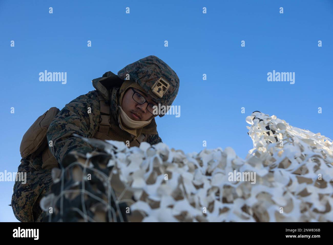 U.S. Marine Lance Cpl. Joab Chavezmancera, a data systems administrator with 3d Battalion, 12th Marines, uses an artic-camouflage net for concealment during Artillery Relocation Training Program 22.4 at the Yausubetsu Maneuver Area, Hokkaido, Japan, Jan. 30, 2023. The skills developed at ARTP increase the proficiency and readiness of the only permanently forward-deployed artillery unit in the Marine Corps, enabling them to provide precision indirect fires. Chavezmancera is a native of Lehi, Utah. Stock Photo