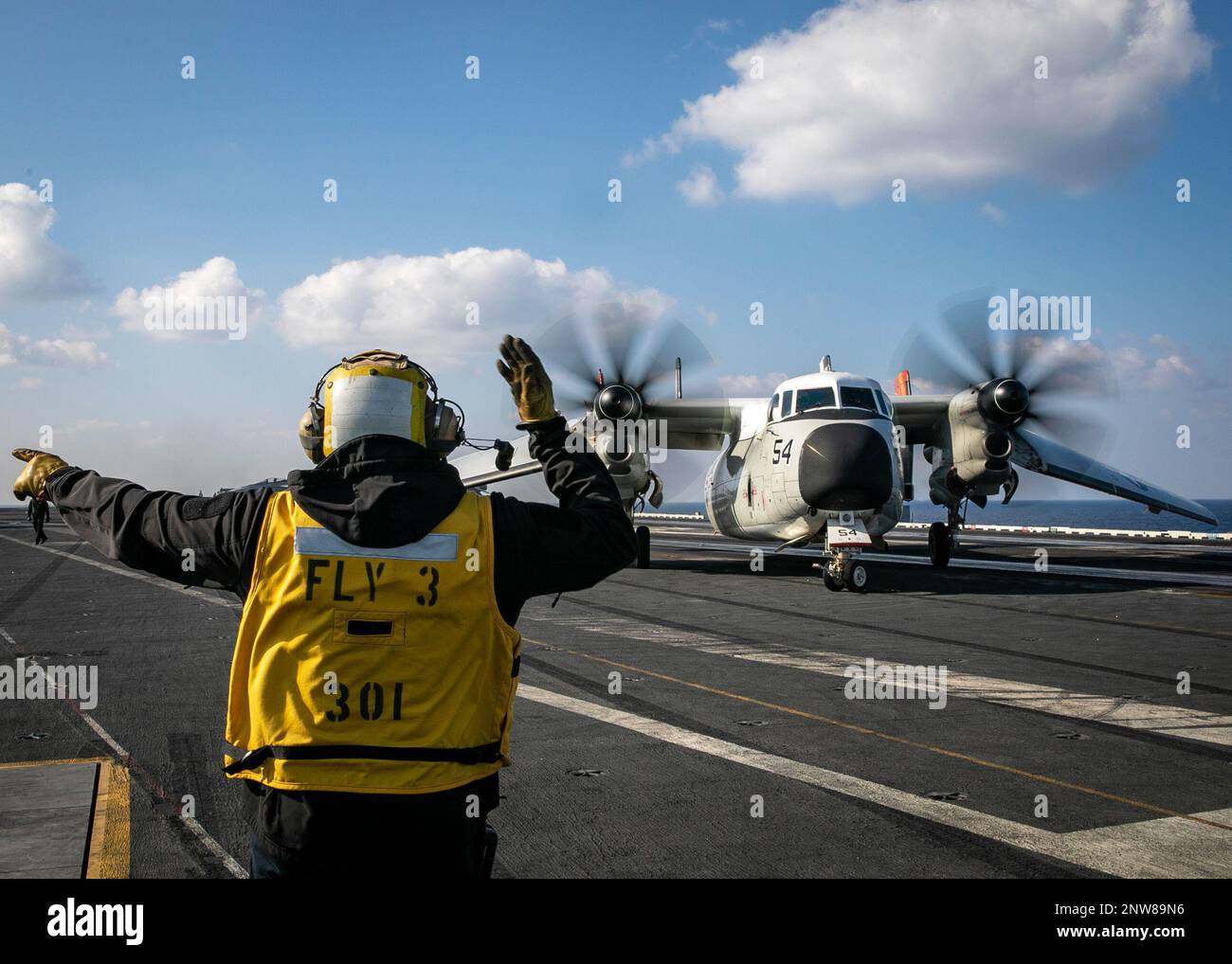 230123-N-EL850-2068 Ionian Sea (Jan. 23, 2023) Aviation Boatswain’s Mate (Handling) 1st Class Joe Oforiatta, assigned to the Nimitz-class aircraft carrier USS George H.W. Bush (CVN 77), directs a C-2A Greyhound aircraft, attached to Fleet Logistics Support Squadron (VRC) 40 during flight operations,  Jan. 23, 2023. Carrier Air Wing (CVW) 7 is the offensive air and strike component of Carrier Strike Group (CSG) 10 and the George H.W. Bush CSG. The squadrons of CVW-7 are Strike Fighter Squadron (VFA) 143, VFA-103, VFA-86, VFA-136, Carrier Airborne Early Warning Squadron (VAW) 121, Electronic Att Stock Photo