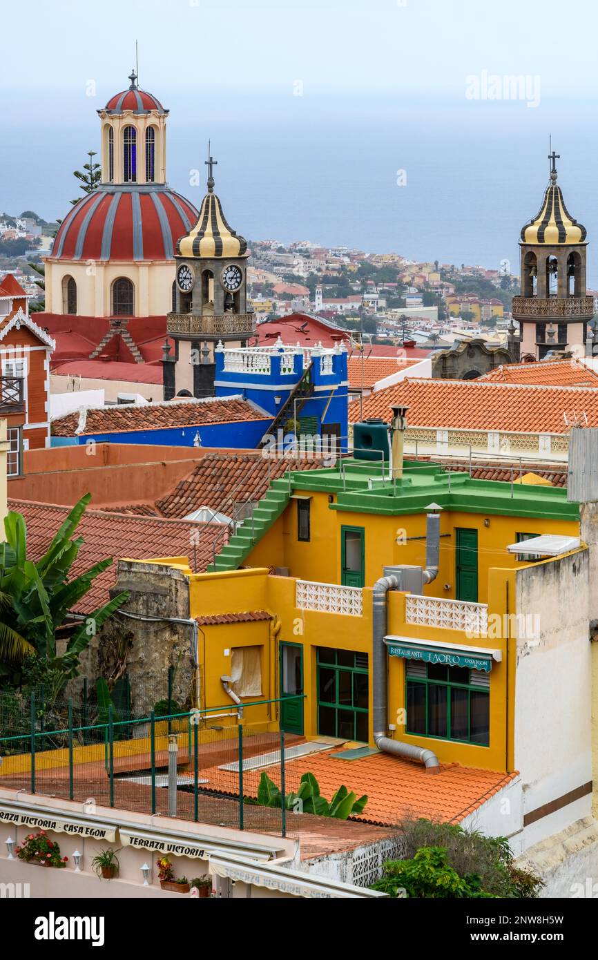 The ornate dome and cupolas of Iglesia de La Concepción rise over the terracotta roofs and brightly coloured buildings of La Orotava in Tenerife. Stock Photo