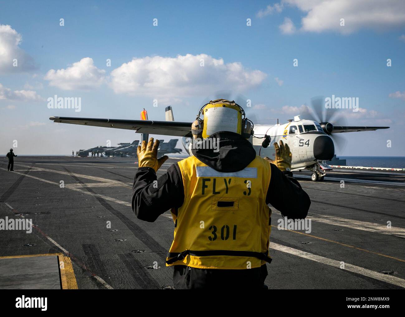 230123-N-EL850-2049 Ionian Sea (Jan. 23, 2023) Aviation Boatswain’s Mate (Handling) 1st Class Joe Oforiatta, assigned to the Nimitz-class aircraft carrier USS George H.W. Bush (CVN 77), directs a C-2A Greyhound aircraft, attached to Fleet Logistics Support Squadron (VRC) 40 during flight operations, Jan. 23, 2023. Carrier Air Wing (CVW) 7 is the offensive air and strike component of Carrier Strike Group (CSG) 10 and the George H.W. Bush CSG. The squadrons of CVW-7 are Strike Fighter Squadron (VFA) 143, VFA-103, VFA-86, VFA-136, Carrier Airborne Early Warning Squadron (VAW) 121, Electronic Atta Stock Photo