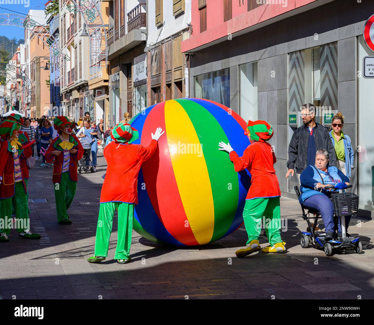 Colourful clowns roll a giant inflatable ball through the streets of San Cristobal de La Laguna in Tenerife as part of the La Noche en Blanco festival Stock Photo