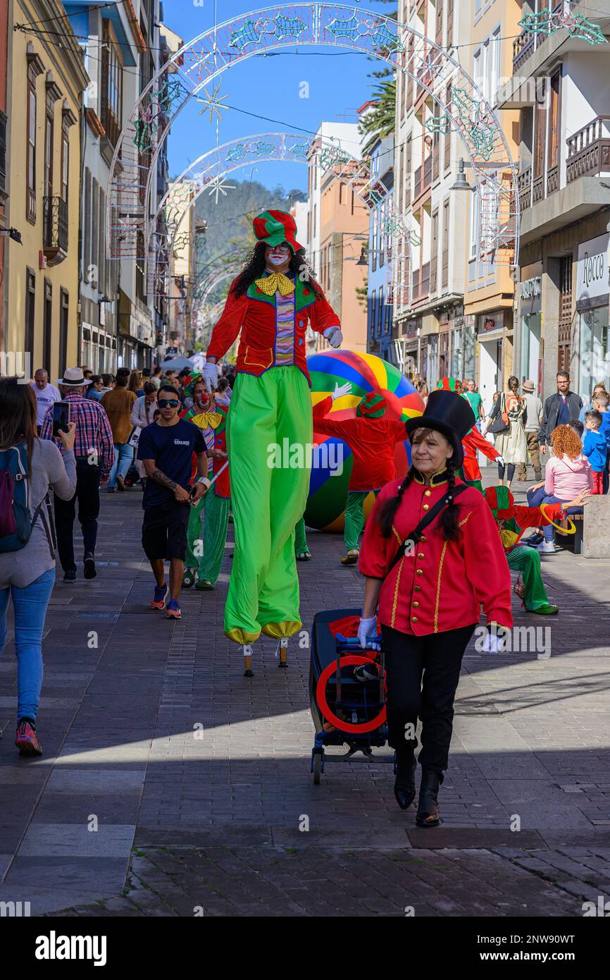 A colourful clown stiltwalker leads a procession of clowns through the streets of San Cristobal de la Laguna in Tenerife during the La Noche en Blanco Stock Photo