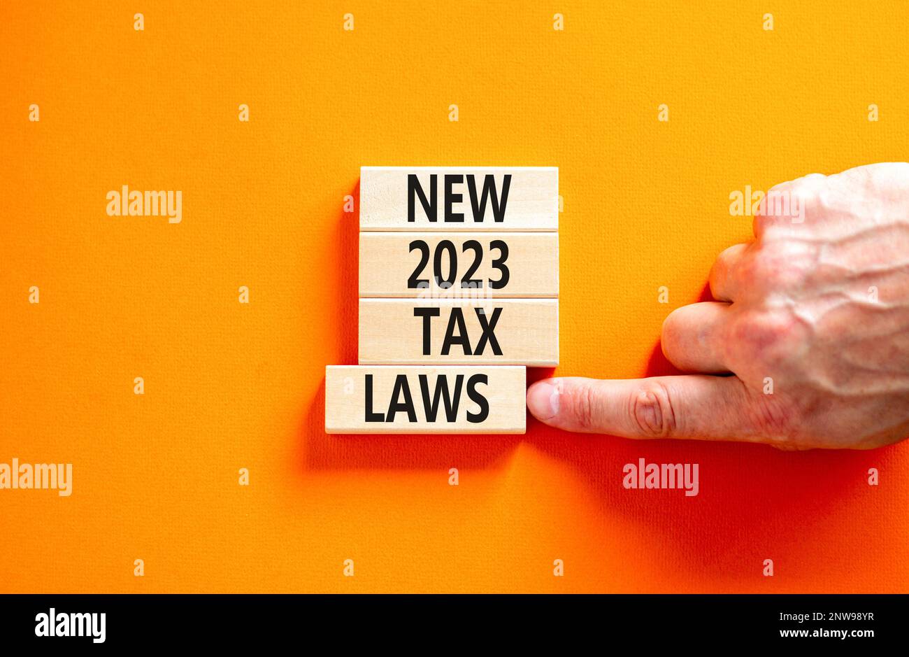 New 2023 tax laws symbol. Concept words New 2023 tax laws on wooden blocks. Beautiful orange table orange background. Businessman hand. Business new 2 Stock Photo