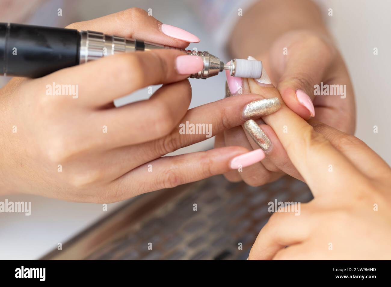 Closeup of manicurist sanding the acrylic nails of a customer. A nail technician performs a manicure in a spa or salon. Cosmetic beauty gel nails Stock Photo