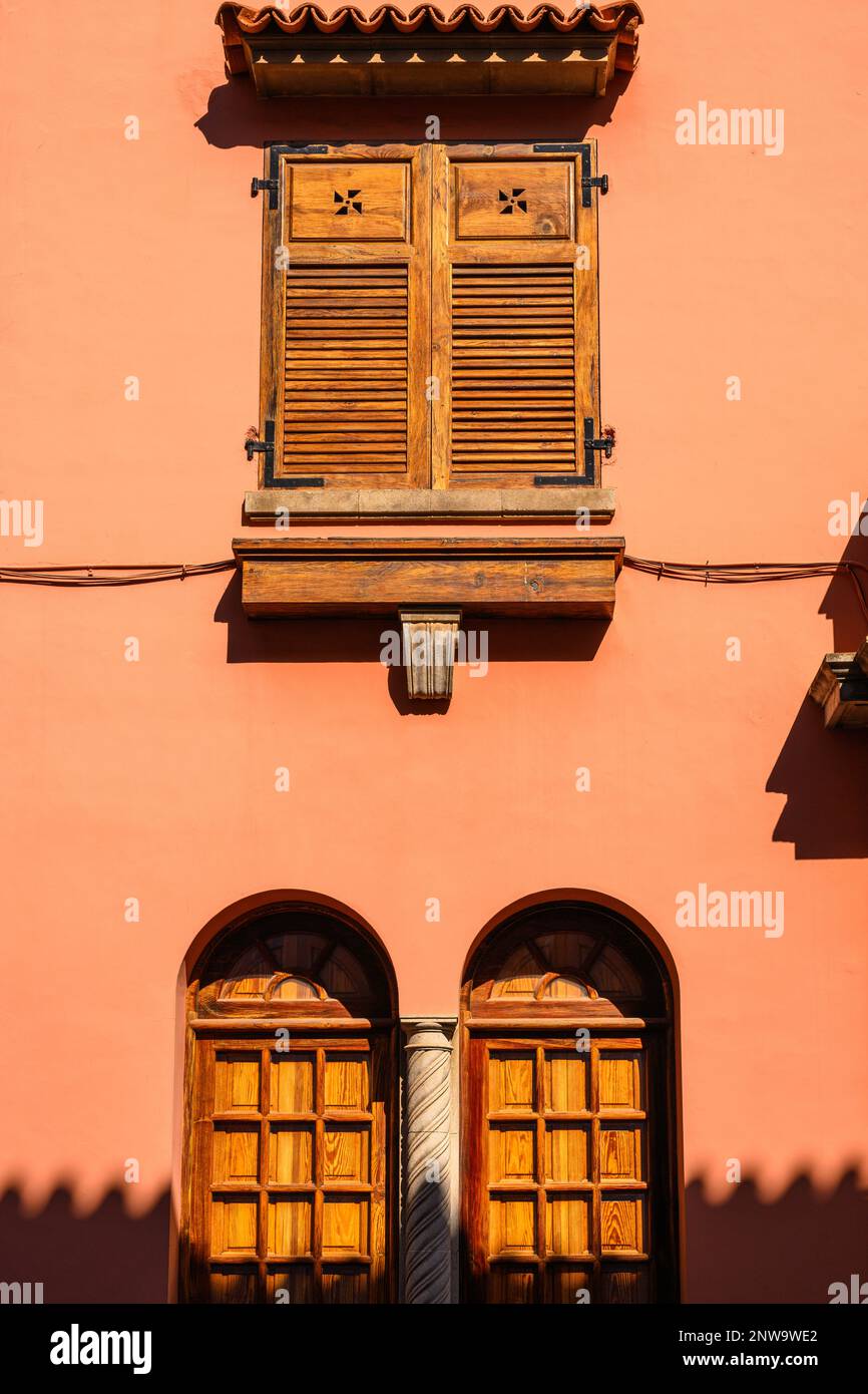 Bright afternoon sunshine lights up the traditional Canarian wooden shutters on an ochre colourd building in Calle San Agustin, La Laguna, Tenerife Stock Photo