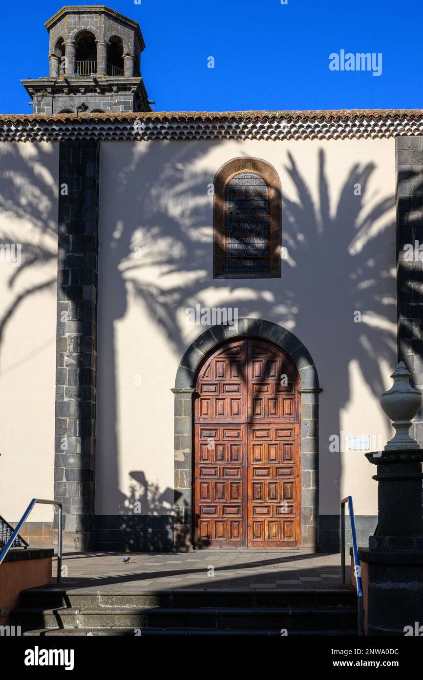 Afternoon sun casts palm tree shadows onto the wall of La Laguna's Iglesia de la Concepción in Plaza Doctor Olivera. Stock Photo