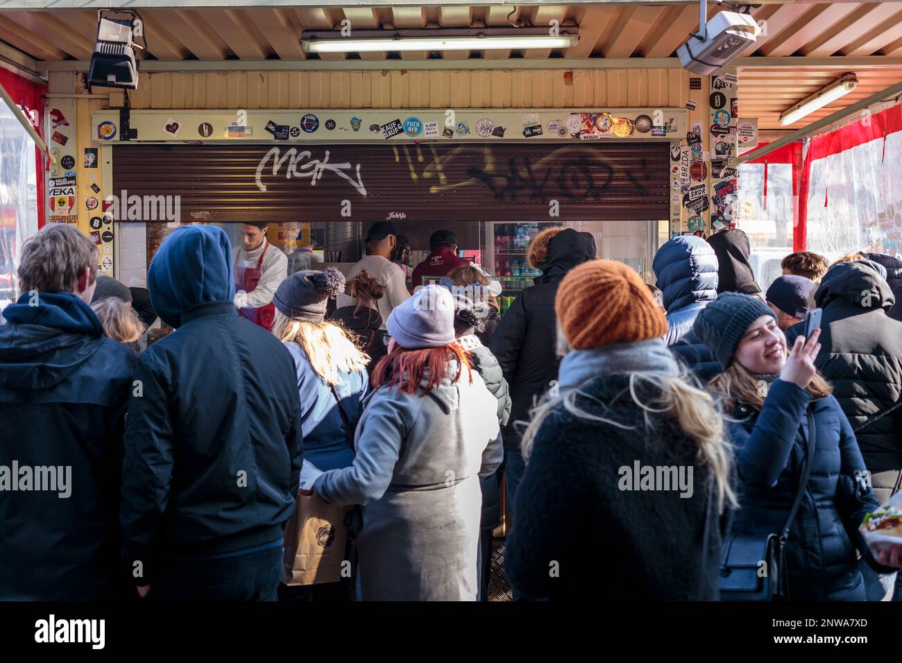 Tourists queue in large numbers during a cold and sunny day at the famous Mustafa's Gemüse Kebap on Mehringdamm, Kreuzberg, Berlin, Germany. Stock Photo