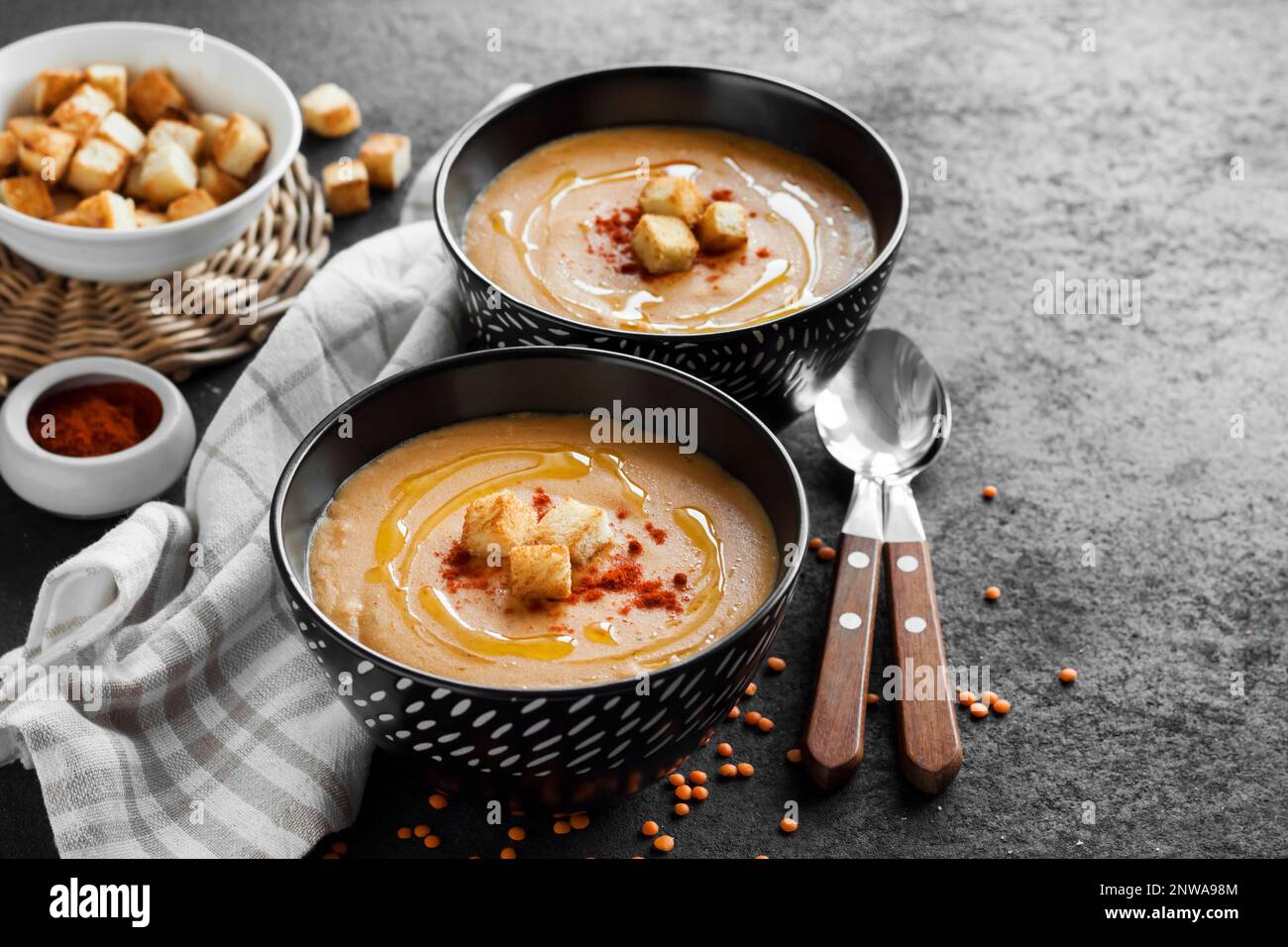 Lentil cream soup with paprika and crouton in black ceramic bowls on dark background. Copy space Stock Photo