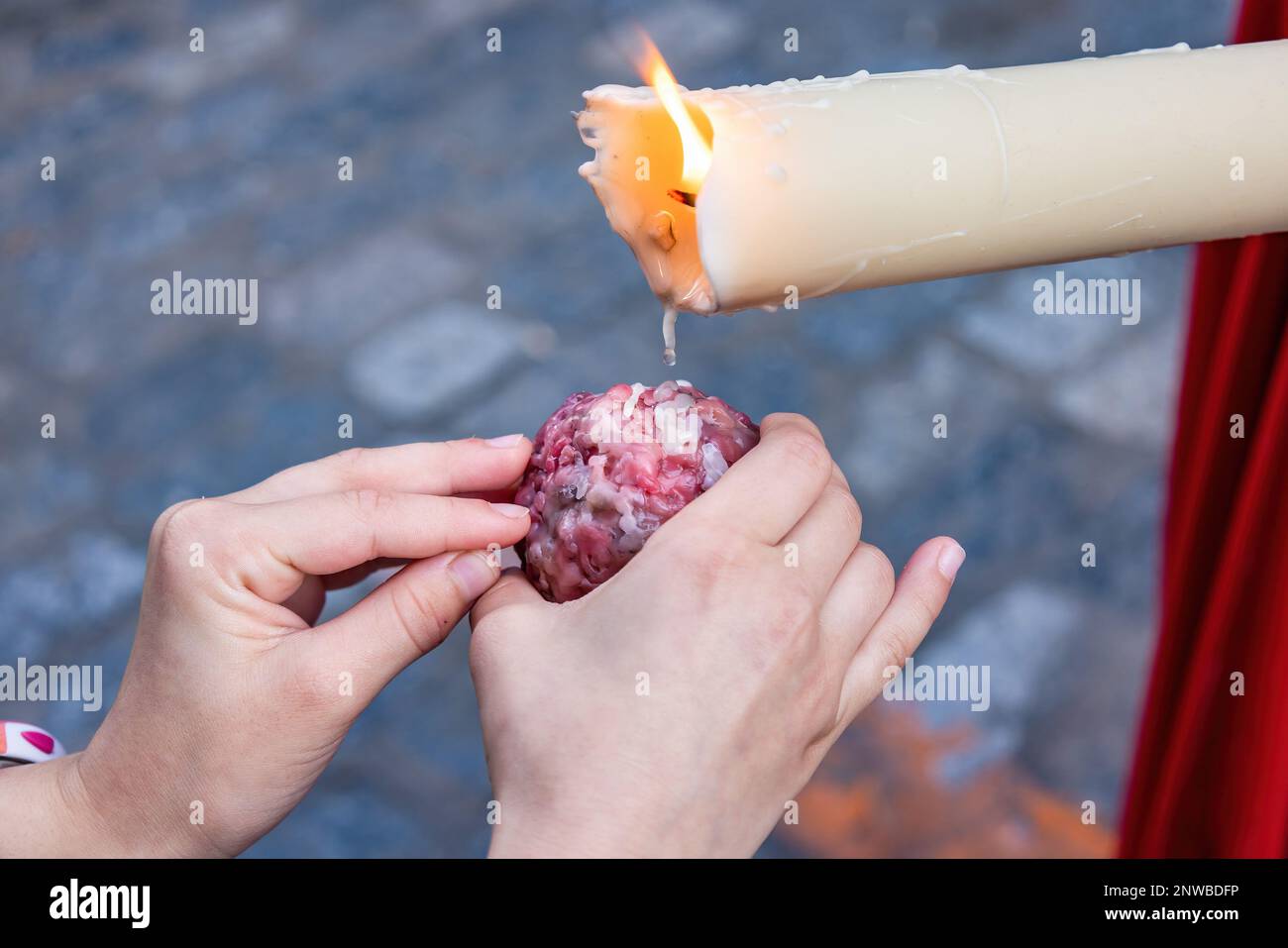 Close Up of the hand of a girl kid collecting wax for his wax-ball during the Holy Week procession. Stock Photo